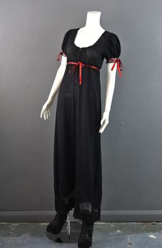 Hark back to the era of the gothic novel and become the heroine of your story with our Regency inspired Morland dress!Swoon in ankle length stretchy striped black lace with a sheer lace hem, low cut neckline for heaving bodices, and dainty lace trimmed short puff sleeves.The high empire waist is trimmed with lace with scarlet red satin ribbon allowing for a adjustable fit, and the sleeves are similarly adaptable.The bust of the dress is decorated with a black lace motif, and fastens with four sm Black Regency Dress For Costume Party, Black Regency Style Dress For Costume Party, Black Fitted Regency Style Dress, Beatrice Otgw, Gothic Regency, Gothic Novel, Dress With Puff Sleeves, Lace Trim Shorts, Empire Waist Dress