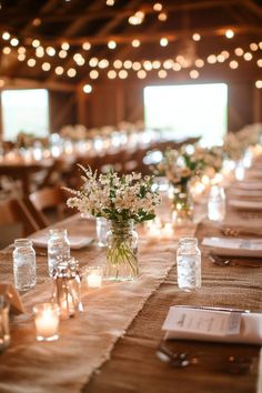 the tables are set up with mason jars and candles for centerpieces on each table