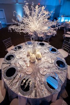 the centerpieces are decorated with white flowers and silver plates