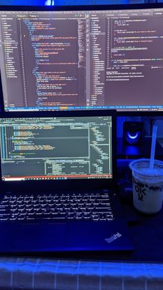 a laptop computer sitting on top of a desk next to a cup of coffee and monitor