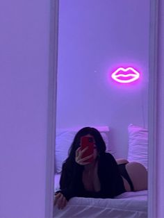 a woman taking a selfie in front of a mirror with her cell phone and lipstick on the wall