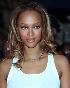 a close up of a person wearing a white tank top and choker necklace on her neck