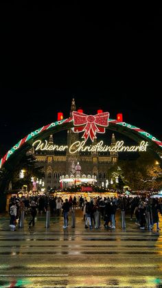 people are standing in front of an arch decorated with lights and christmas decorations at night