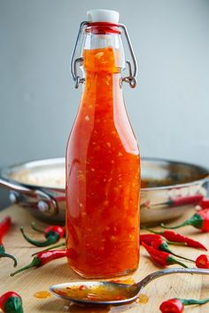 a glass bottle filled with hot sauce sitting on top of a wooden table