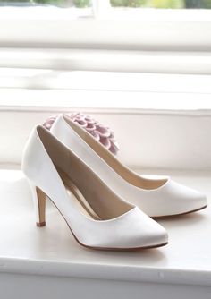 a pair of white high heel shoes sitting on top of a window sill