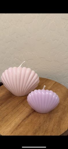 two pink seashells sitting on top of a wooden table