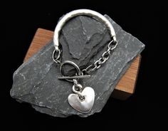 Silver Cuff Bracelet, Heart Charm Bracelet, Silver Heart Bracelet, Silver Heart Charm Bracelet, Silver Toggle Clasp Bracelet, Gift For Her Silver cuff bangle  The Chain is made from stainless steel,  The rest of the bracelet is zamak. Toggle clasp fastening and heart charm. Its  antique silver in colour which is a vintage aged tone, not a bright shiny silver. The bracelet is solid so has a good weight to it. Crafted from a zinc and brass alloy and plated in antique silver which is both hardweari Metal Heart Bracelet With Toggle Clasp As Gift, Heart Shaped Bracelet With Toggle Clasp As Gift, Heart-shaped Charm Bracelet With Toggle Clasp As Gift, Heart Charm Bracelet With Toggle Clasp For Gift, Silver Heart Bracelet With Toggle Clasp, Heart Shaped Toggle Clasp Bracelet For Gift, Silver Heart-shaped Bracelet With Toggle Clasp, Valentine's Day Gift Bracelet With Toggle Clasp, Valentine's Day Heart Bracelet With Toggle Clasp