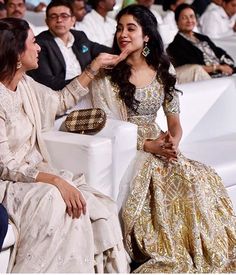 two women sitting next to each other in front of an audience at a fashion show