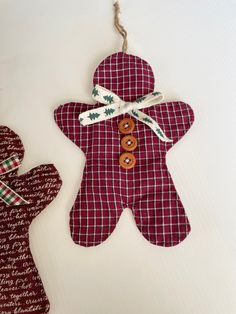 two red and white plaid christmas decorations hanging from strings on a tablecloth covered surface