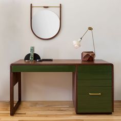 a green desk with a mirror and lamp on it in front of a white wall