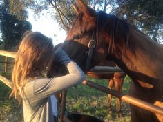 a woman standing next to a brown horse