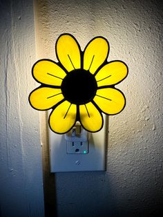 a light that is on the side of a wall with a yellow flower in it