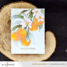 a card with oranges on it sitting on top of a piece of wood next to a tree stump