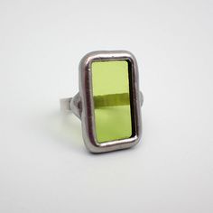 Small, transparent lime green stained glass ring edged in silver. The sterling silver wire band is size 6. This is a one of a kind ring.  Ring Size: US 6 / UK M Center Glass Size: 7/8" x 1/2" Each item by Faerie Glass is 100% uniquely hand-crafted with quality materials that are lead-free. NOTE - All photographs are taken in effort to best represent the actual product. Color of actual jewelry may vary slightly from photographs. Stained Glass Ring, Glass Ring, Glass Rings, Silver Wire, Rings Statement, Kiwi, Lime Green, Statement Rings, Stained Glass