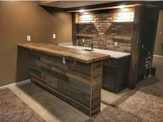 an unfinished kitchen counter made out of pallets and wood planks with brick wall behind it