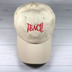 a baseball cap with the word peace on it sitting on a white wooden surface in front of a wall