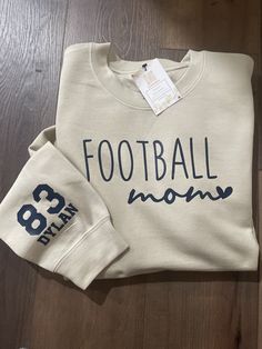 This crew neck sweatshirt makes the perfect gift for football moms. Choose  your size and shirt color from the drop menu below. Make sure to fill out the personalization section with your child's jersey number and name and your choice of font color. This will be added to the sleeve of the shirt. Font colors are navy, black, white, red, gold, bright yellow, forest green, or orange. Email us for a specific color shade.   Adult Unisex  50/50 Fleece Crew Football Mom Sweater, Football Sweatshirts Vinyl, Diy Football Mom Shirts, Football Mom Shirts Ideas Design, Football Mom Shirts Ideas Sons, Sports Mom Shirts Ideas, Football Mom Sweatshirt Ideas, Football Mom Must Haves, Football Shirts Ideas