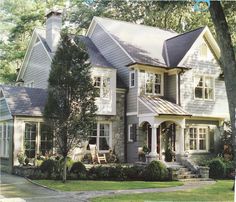 a large house with lots of windows on the front and side of it, surrounded by trees