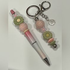 a pen and keychain with flowers on it sitting next to a pair of scissors