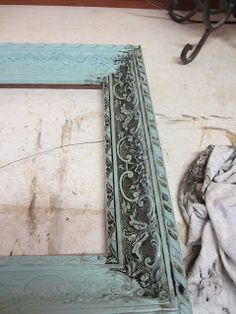 an old wooden frame sitting on the floor next to a piece of cloth and some scissors