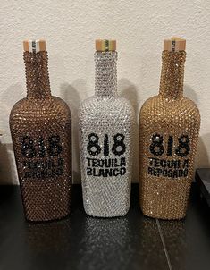 three bottles with bling on them sitting next to each other in front of a wall