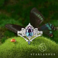 a ring with a blue topaz surrounded by grass and ladybug bugs in the background