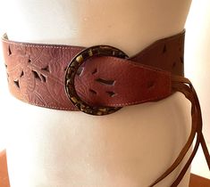 Vintage fashion belts wide brown leather fringed wardrobe accessories cowgirl ITEM DESCRIPTION: Offering this wide brown leather fashion belt. circa estimated 1980s-2000's This adjustable fringed belt features a stencilled leather strap with Tiger's Eye 'stones' (faux?) circling the big round buckle.  The inside belt strap is marked: "L. Leather China".  MEASUREMENTS: This classic hip belt measures approximately 37 1/2 inches full length (including buckle but not including fringe) and 3 inches w Antique Brown Belt Buckle For Festival, Brown Antique Buckle Belt Buckles For Festival, Adjustable Brown Corset Belt With Matching Belt, Adjustable Brown Belts For Festival, Adjustable Brown Belt For Festival, Bohemian Brown Belt Buckles For Festival, Vintage Brown Corset Belt With Belt Loops, Vintage Brown Corset Belt For Festivals, Bohemian Brown Belts For Summer