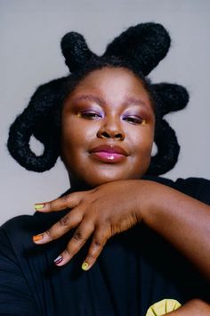 a woman with her hands on her chest, posing for the camera and wearing yellow nail polish