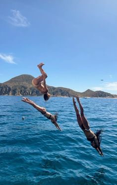 two people diving into the ocean from a boat