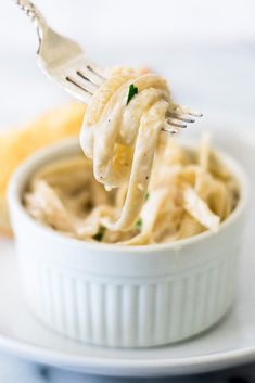 a fork full of macaroni and cheese being held up over the top of a bowl