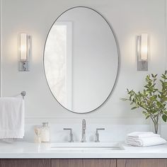 a bathroom sink with a round mirror above it and two lights on the wall next to it