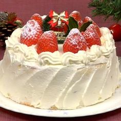 a white cake topped with strawberries on top of a table next to christmas decorations