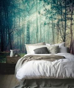 a bedroom with a forest mural on the wall and a bed in front of it