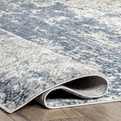 a blue and white rug on the floor with a wooden floor in front of it