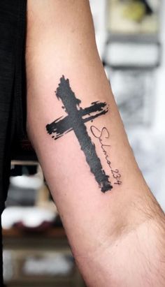 a man with a cross tattoo on his arm