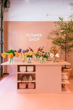 the flower shop is decorated with pink walls and white flooring, along with flowers in vases