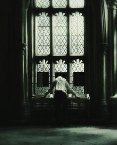 a person sitting on a bench in front of a large window with stained glass panes