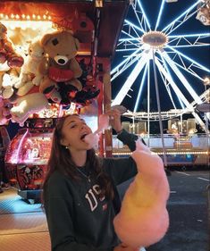 a woman eating cotton candy at an amusement park