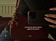 a woman holding a cell phone in her hand with a chain attached to it that says, me and my cherry charm against the world