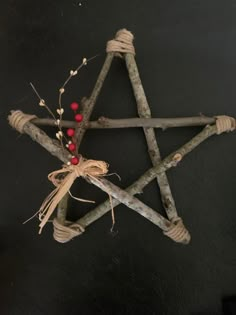 a star made out of sticks with berries tied to the ends and twine around it