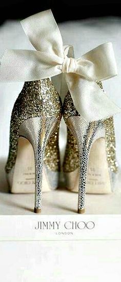 a pair of glittered high heels with a white bow on the top are sitting on a box