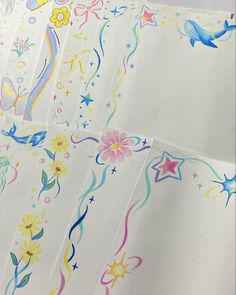 four sheets of white paper with colorful designs and stars on the side, all lined up together