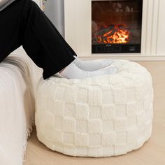 a person sitting on a bean bag chair in front of a fire place with their feet up