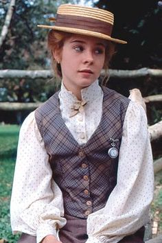 a woman wearing a vest and hat in front of a green frame with an image of her