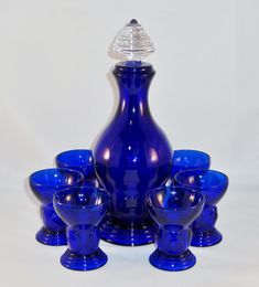 a blue glass vase sitting on top of a table next to cups and saucers