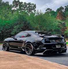 the black sports car is parked on the side of the road in front of some trees