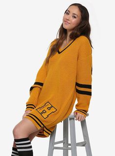 a woman sitting on top of a stool wearing a yellow sweater and black striped socks