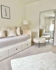 a bedroom with a bed, mirror and white furniture