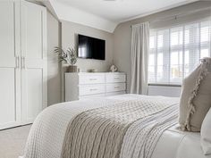 a bedroom with white furniture and large windows