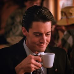 a man in a suit and tie holding a coffee cup